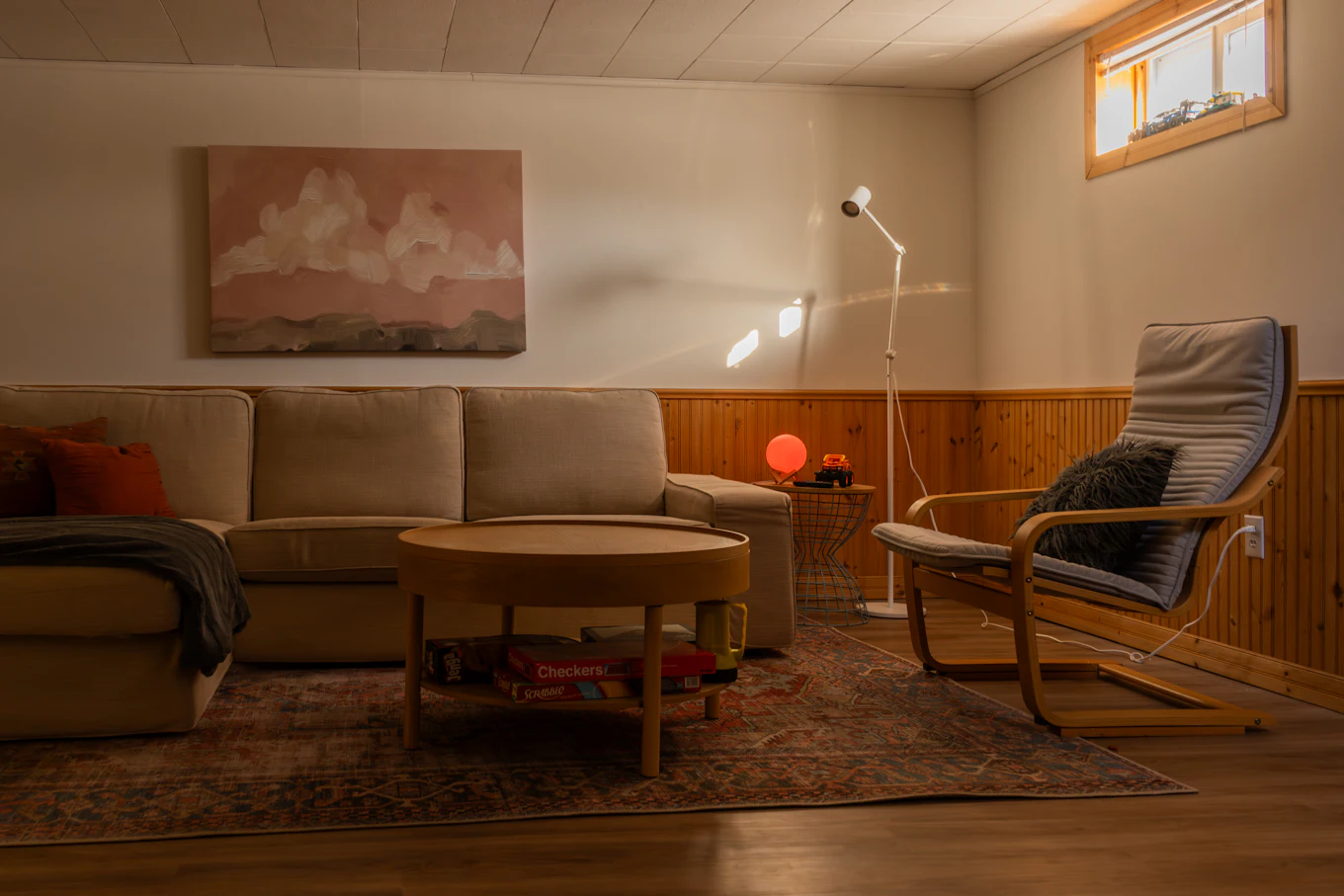 Vardagsrum med soffa, golvlampa vid fåtöljen och liten bordslampa i kvällsljus